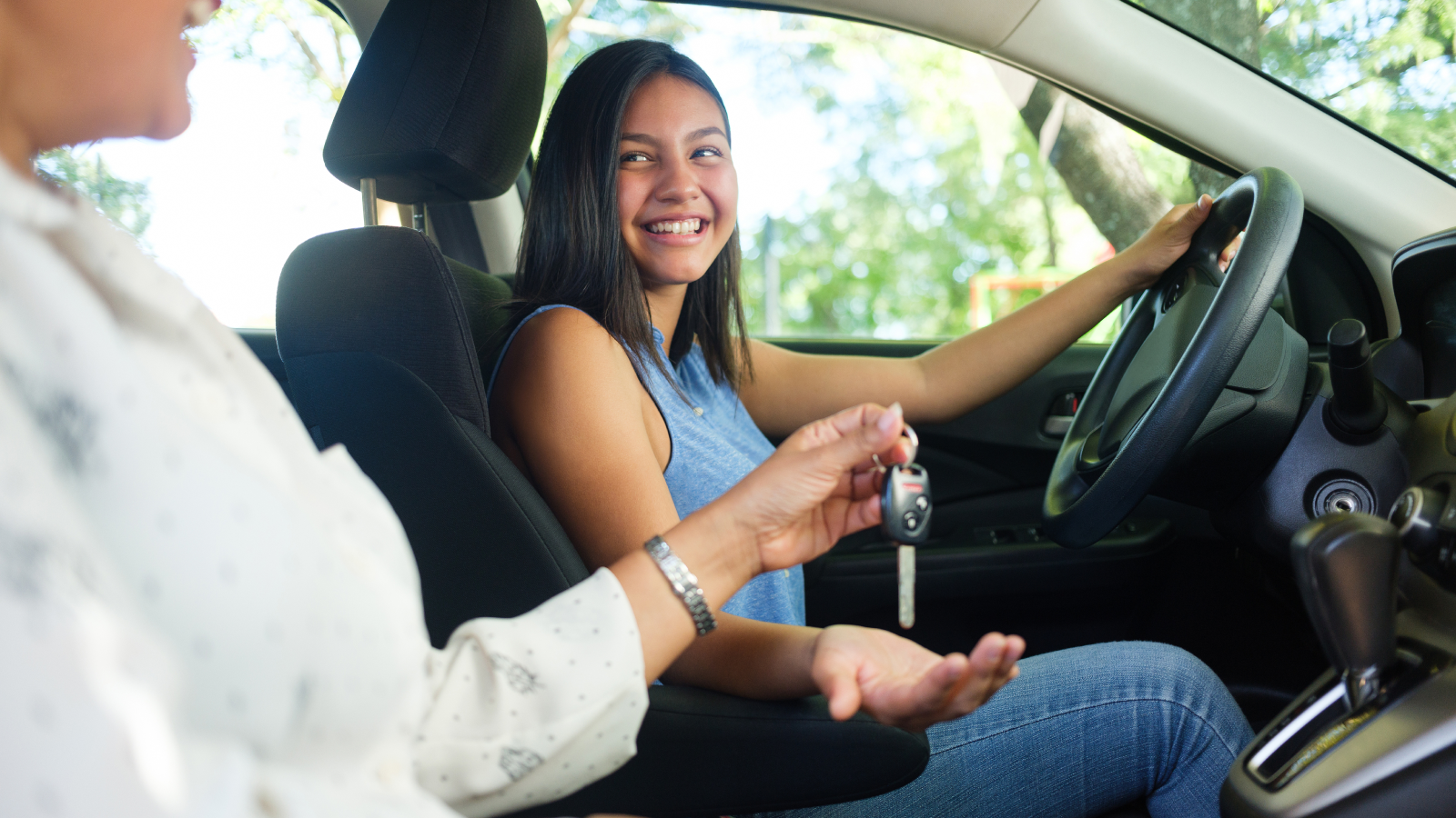 Passenger in car handing new driver the keys. 