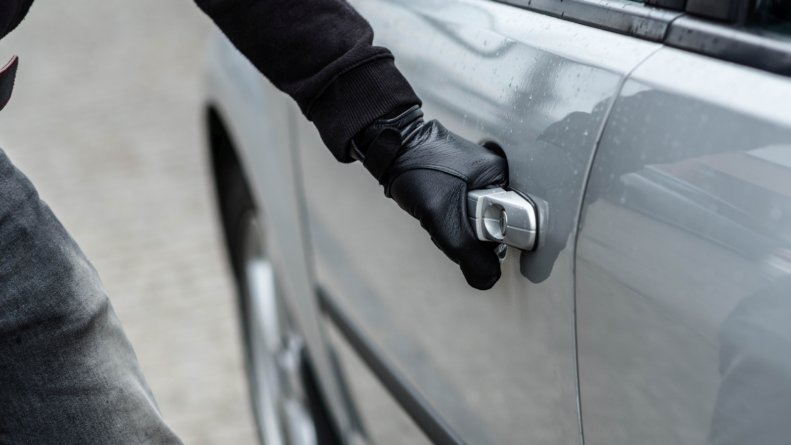 Burglar with gloves opening car door.