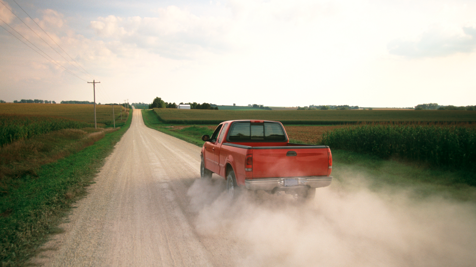 Red pickup truck traveling down a dirt road in rural Southern Georgia, USA.