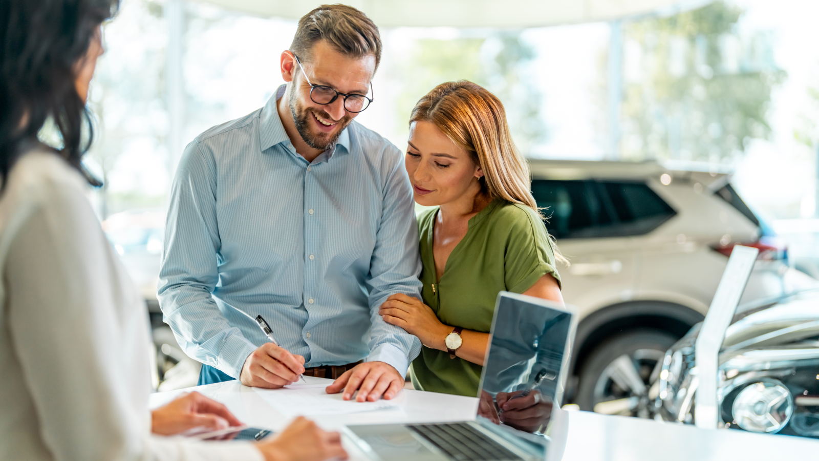 Couple finalizing purchase of new car at dealership.