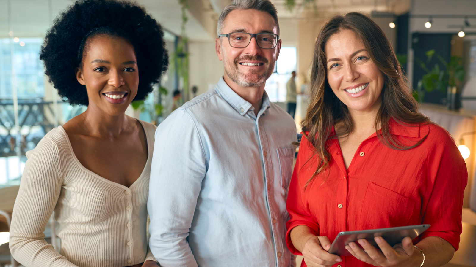 Three insurance professionals smiling and looking at the camera in an office setting.