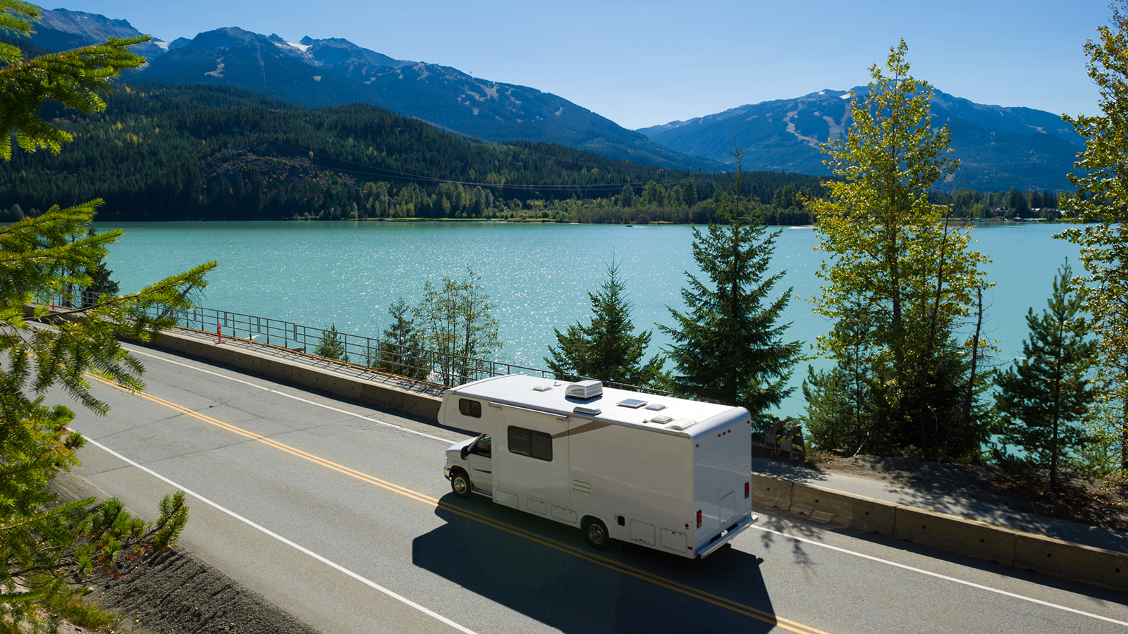 A picture of an RV driving next to a body of water.