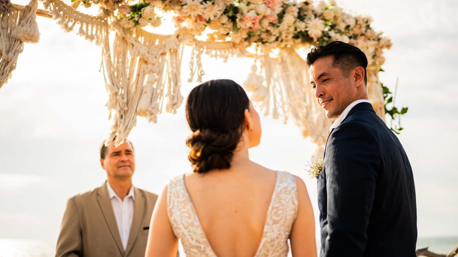 A bride and groom gaze lovingly at each other in front of a wedding altar.