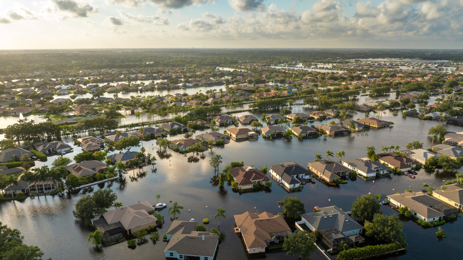 Aerial view of a flooded neighborhood with homes partially underwater, showing water damage after severe weather and torrential rainfall.