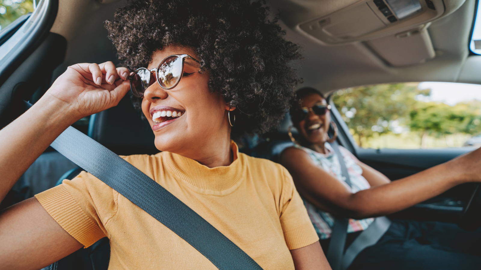 Woman enjoying car ride looking out the window with friend.