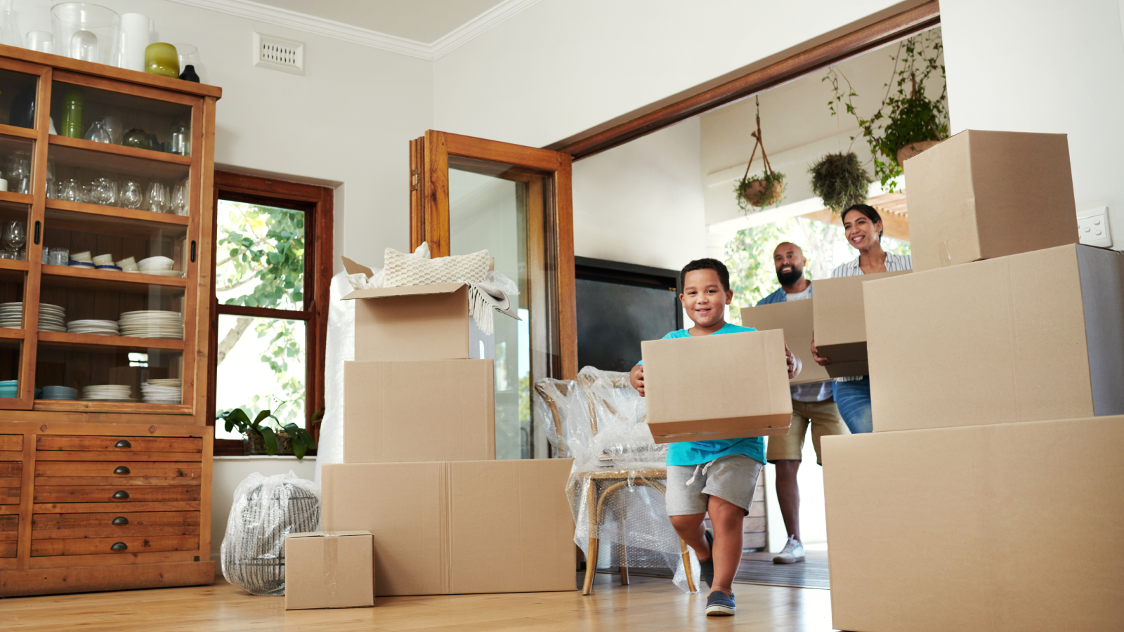 Small boy moving boxes into new home with parents.