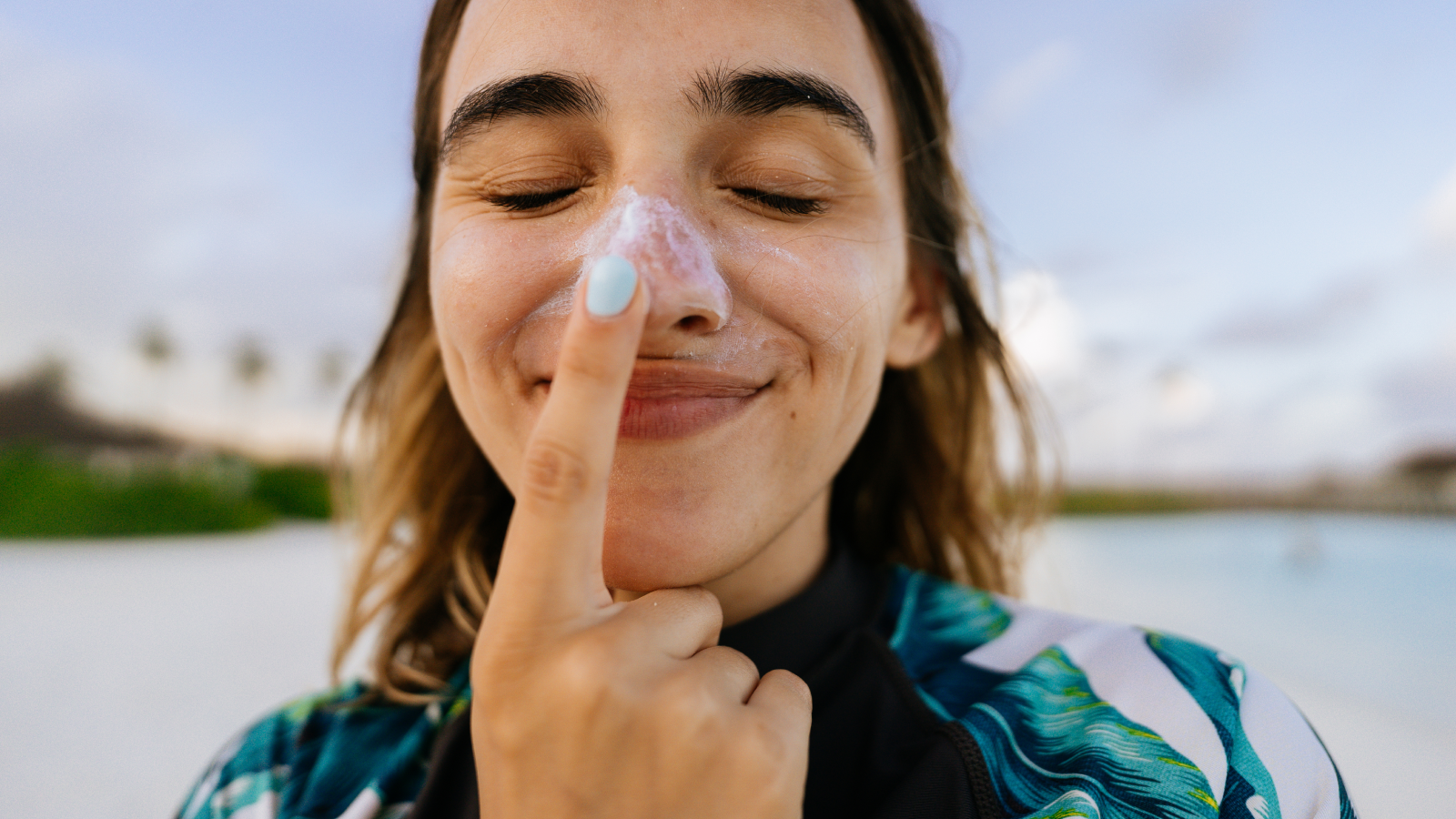Woman applies sunscreen to her face.