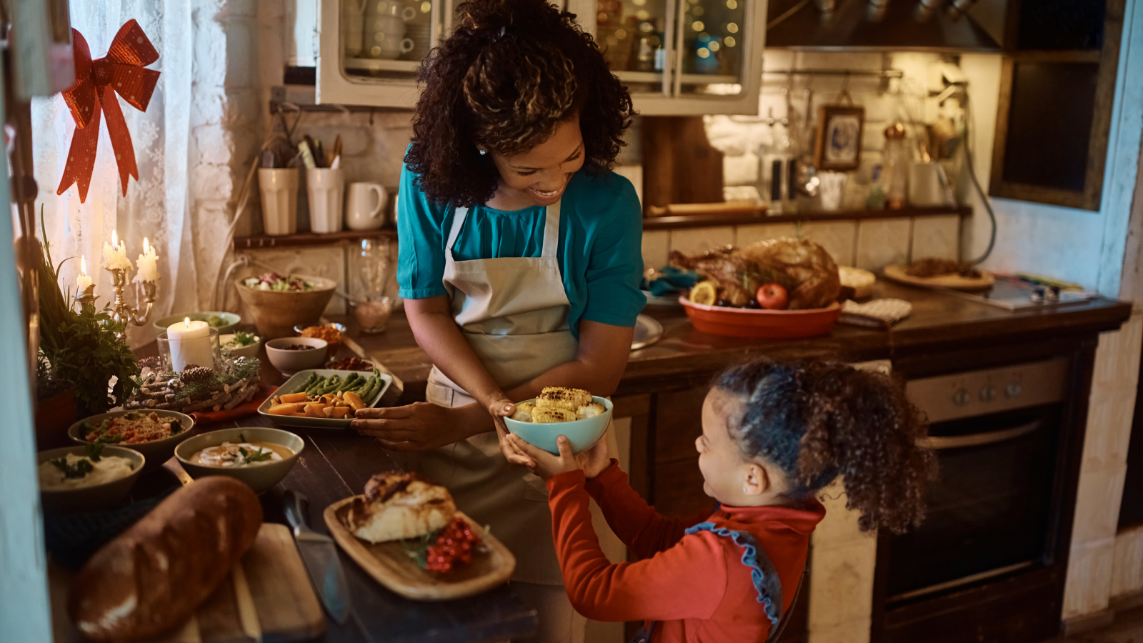 A picture of a woman giving a bowl of food to a little girl.