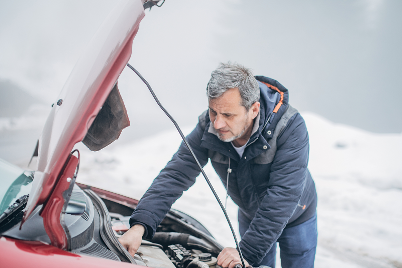Man looking at his car with the hood open.