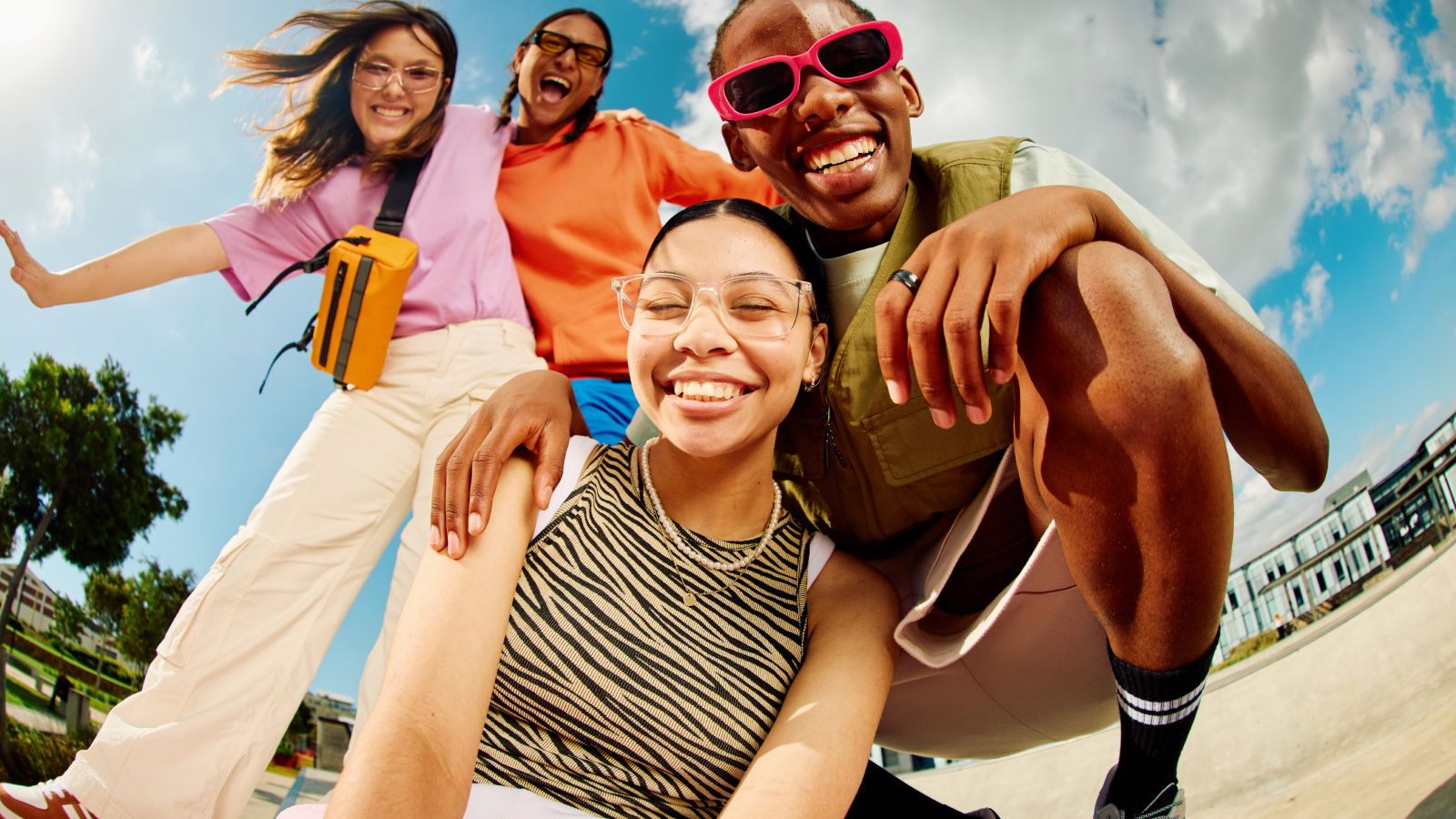Four Gen Z friends in their early twenties smiling and posing playfully in front of a fisheye lens.