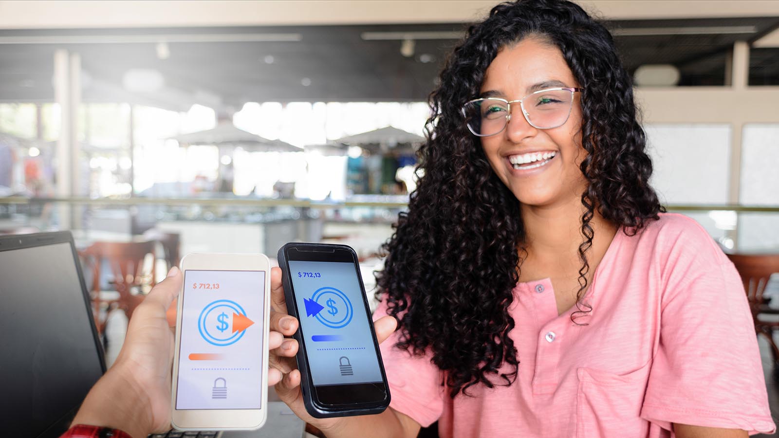 Woman smiles while showing her friend a savings screen on her cell phone.