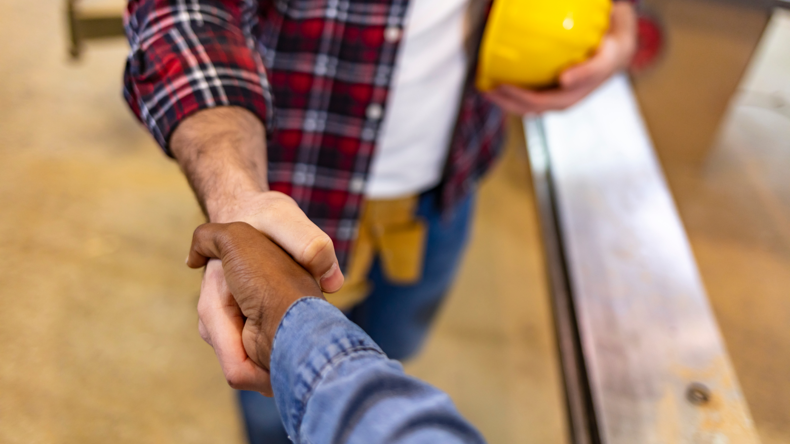 Customer shaking hands with contractor holding construction head gear.