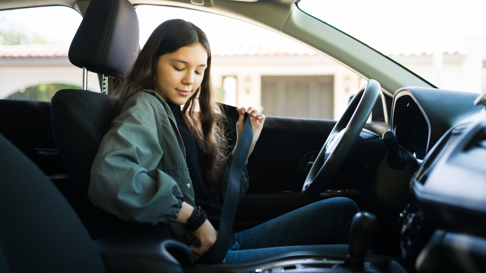 Young female driver buckling up in vehicle. 