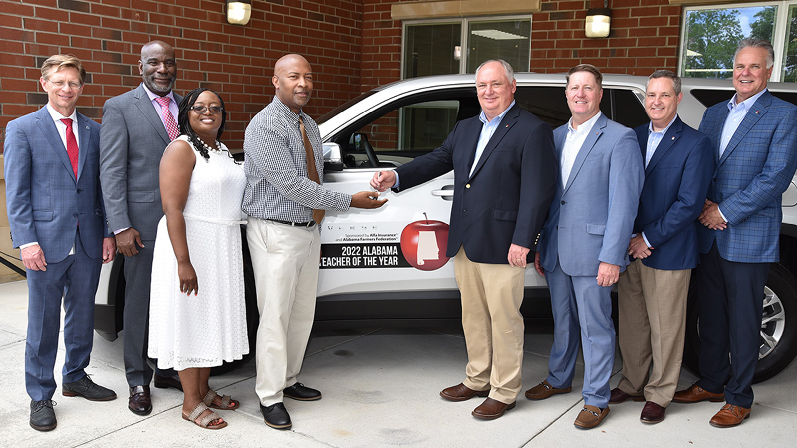 A picture of the 2022 teacher of the year from Booker T Washington receiving a car from Alfa.