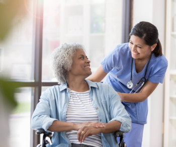 A nurse pushing an elderly woman in a wheelchair
