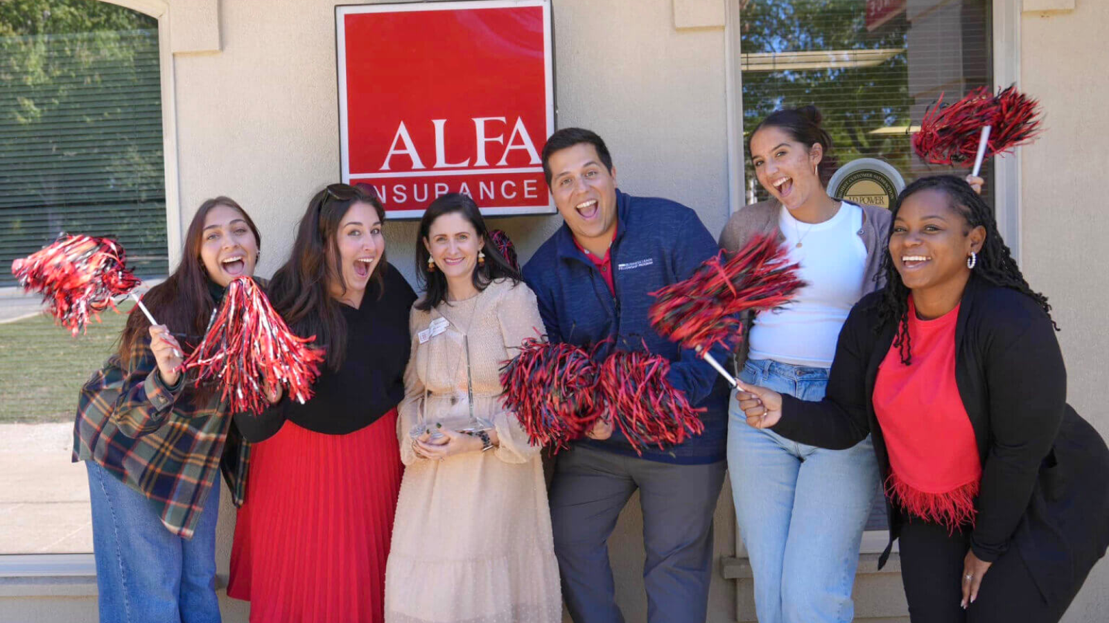 Insurance agent Stephanie Graham and colleagues show community spirit, shaking pom-poms in front of an Alfa Insurance office.