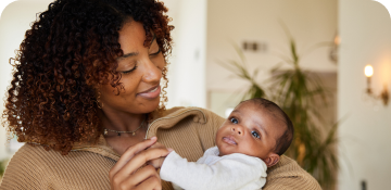 A mother holding and looking at her baby.