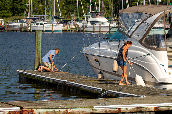 Couple docking large boat at marina.