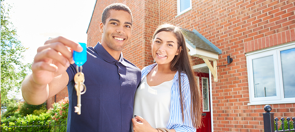 A picture of a couple holding the keys to a home.