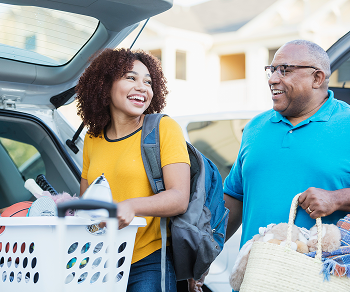 Two people loading the trunk of a car with items.