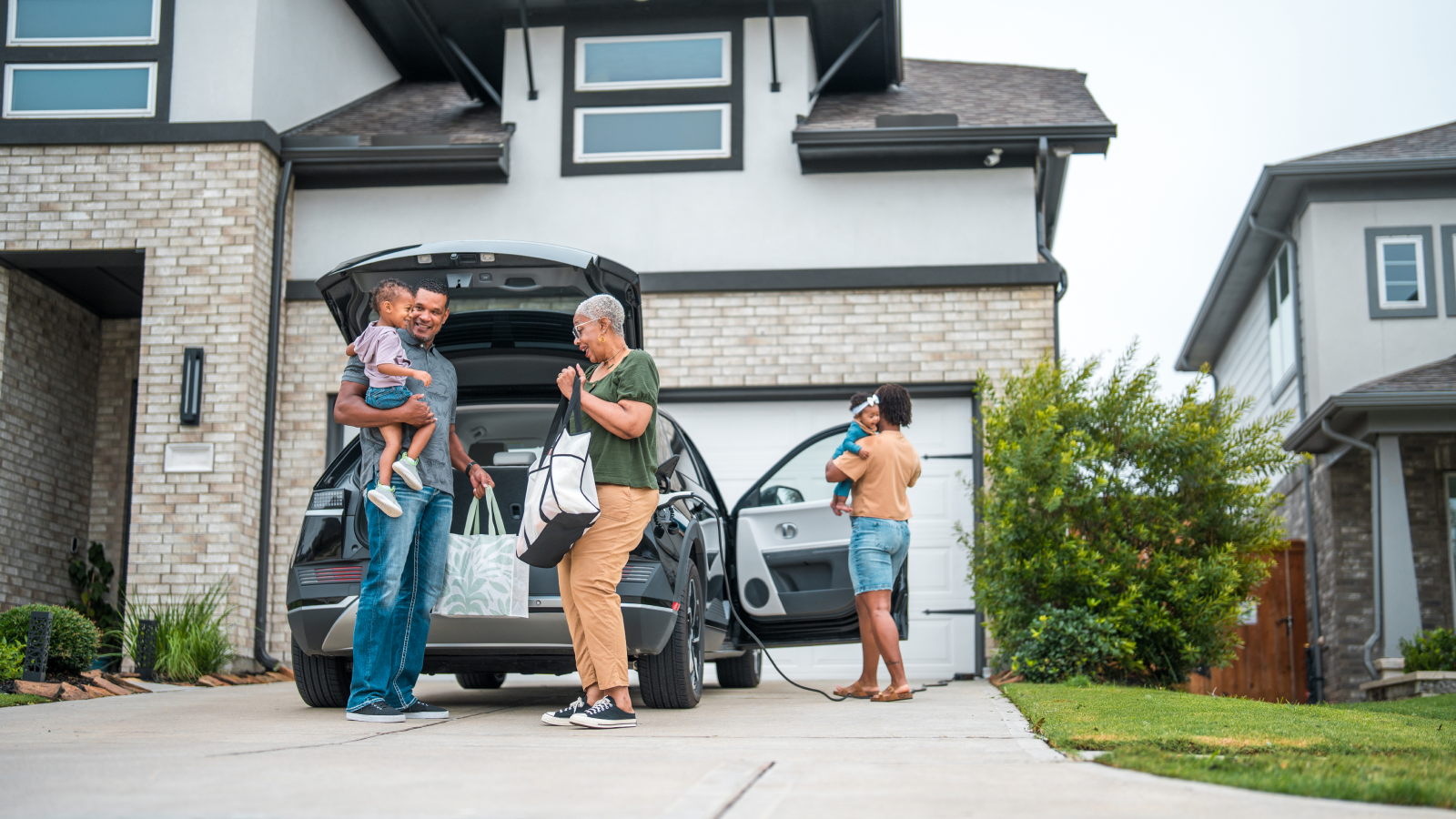 Smiling family unloading the car outside of their home.