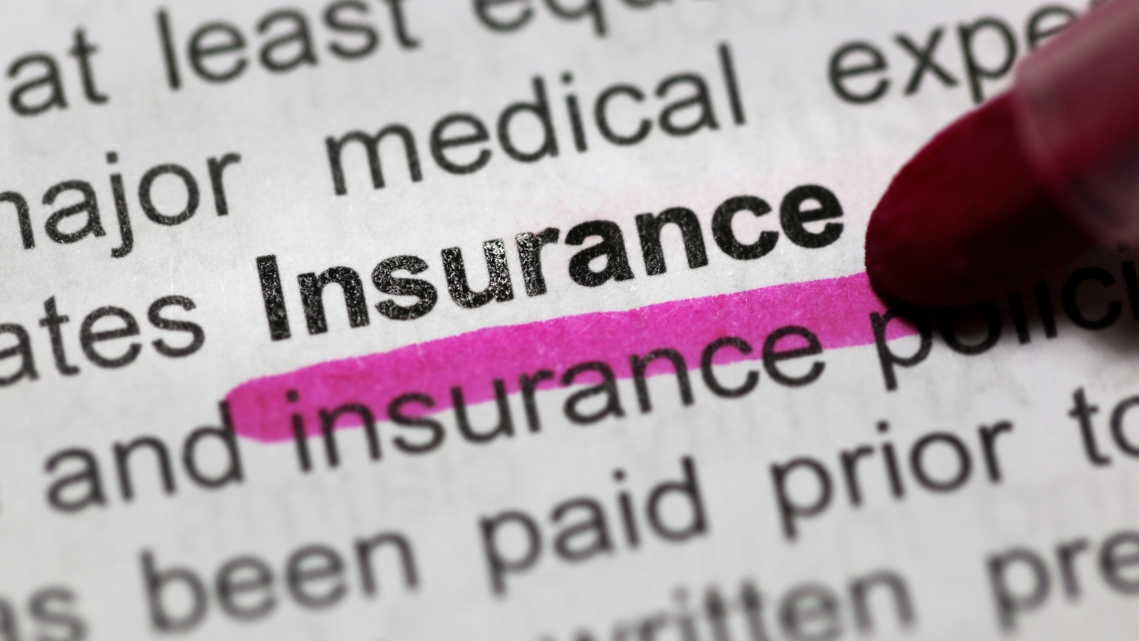 Close-up of the word 'insurance' highlighted in pink in a book.