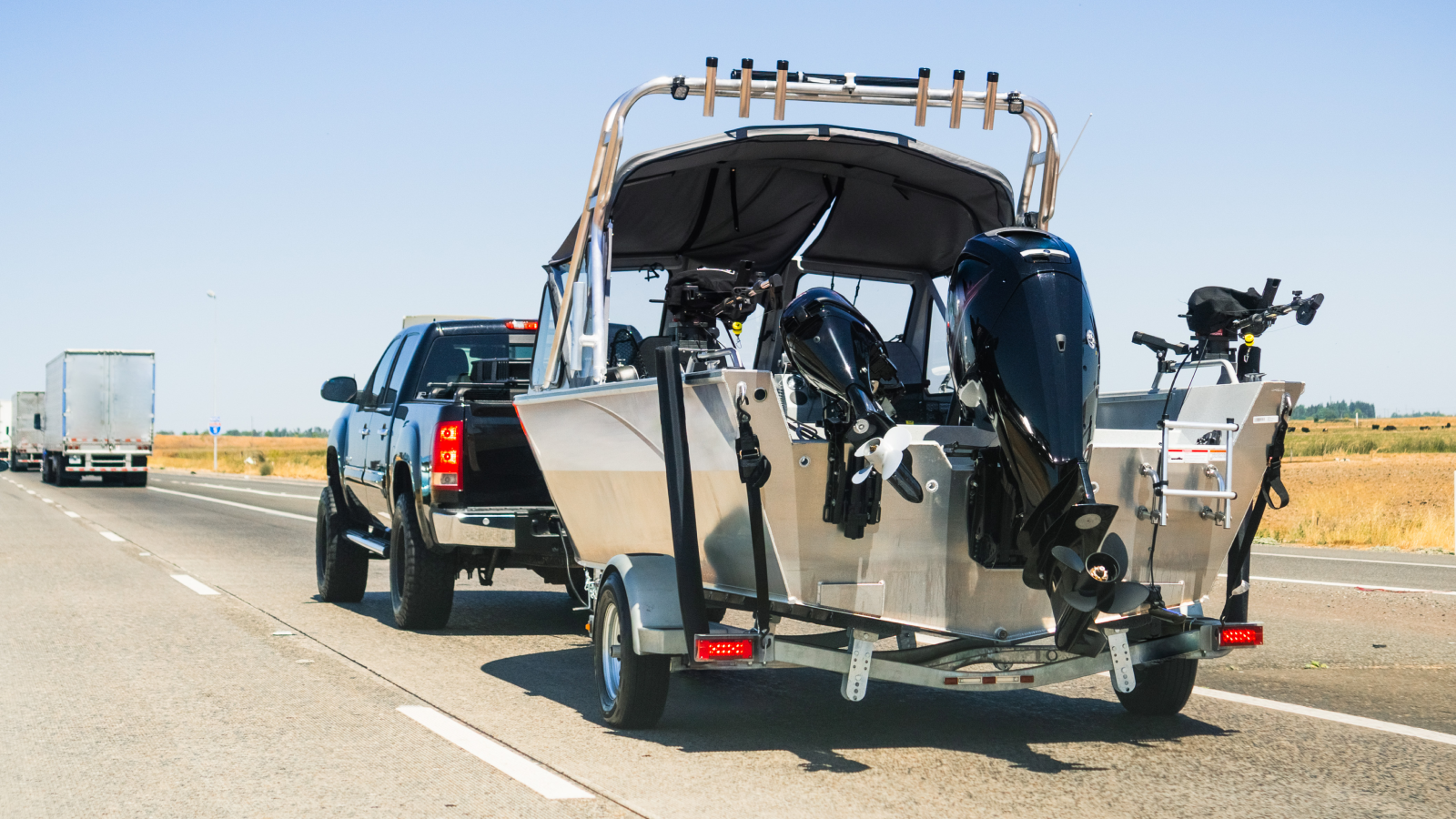 Towing boat behind pickup truck on highway.