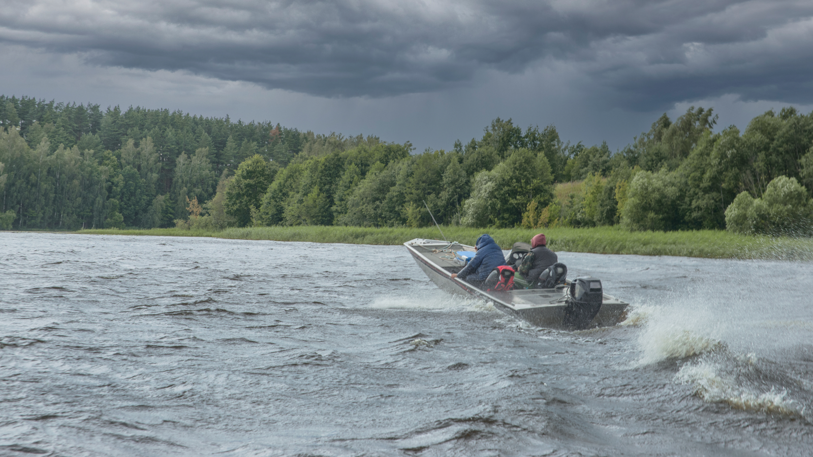 Fishing boat on lake with clouds and stormy conditions present.  